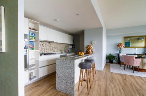 a kitchen with white cabinets and a counter with stools at Departamento Grand 4H-154 in Guadalajara