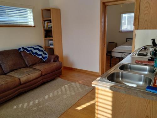 eine Küche und ein Wohnzimmer mit einem Sofa und einem Waschbecken in der Unterkunft Sky Harbor Cabin - Homer Seaplane Base in Homer