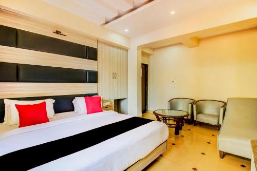 a hotel room with a large bed and chairs at Collection O 30965 Baga Residency in Baga