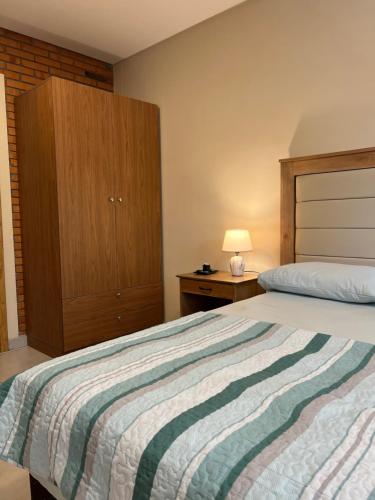 a bedroom with a large bed and a wooden cabinet at Aparthotel Los Laureles in San Lorenzo de la Frontera
