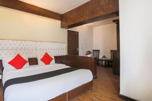 a bedroom with a large white bed with red pillows at Hotel O Arora shoppers park in Ghaziabad