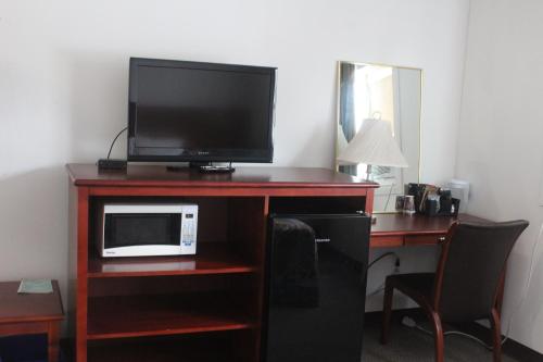 a room with a desk with a microwave and a television at Esterhazy Motor Hotel in Esterhazy