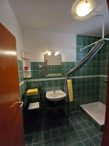 a green tiled bathroom with a sink and a shower at Apartments by the sea Ivan Dolac, Hvar - 21269 in Jelsa
