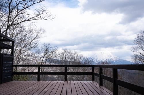 a wooden deck with a view of a snow covered mountain at Niseko HyKrots IKIGAI Village in Rankoshi