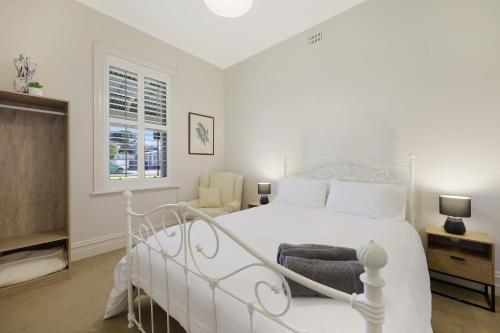a white bedroom with a white bed and a window at HiderWay - Perched overlooking Warrnambool's landmarks in Warrnambool