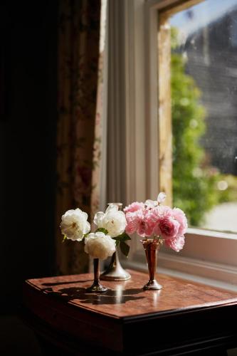 three vases filled with flowers sitting on a window sill at Clifton Homestead in Ranelagh
