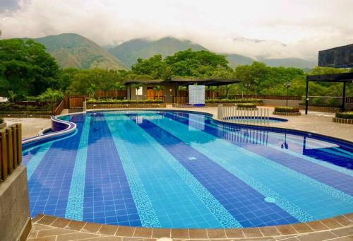 une grande piscine bleue avec des montagnes en arrière-plan dans l'établissement El Paraiso Del Oasis, à Medellín