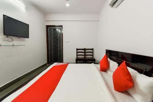 a bedroom with a bed with red pillows and a flat screen tv at Flagship Sitar Guest House in Rudrapur