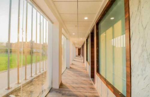 un couloir vide dans un bâtiment doté de grandes fenêtres dans l'établissement Flagship Sitar Guest House, à Rudrapur