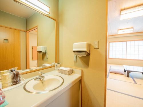 a bathroom with a sink and a mirror at Ryokan Hakura in Yamanouchi
