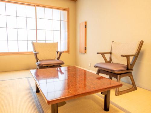 two chairs and a wooden table in a room at Ryokan Hakura in Yamanouchi