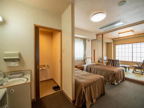 a hotel room with two beds and a sink at Ryokan Hakura in Yamanouchi