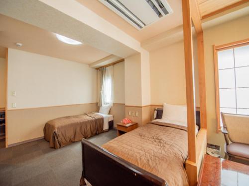 a bedroom with two beds and a window at Ryokan Hakura in Yamanouchi