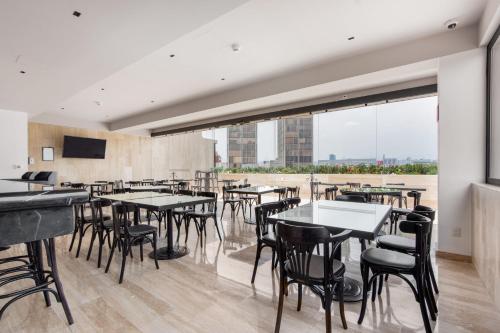 a restaurant with tables and chairs and a large window at Hotel Elements by Marquis in Mexico City
