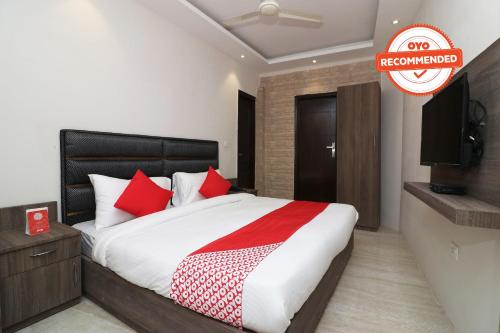 Schlafzimmer mit einem Bett mit roten Kissen und einem Flachbild-TV in der Unterkunft OYO Flagship Hotel Madhurapuri in Kozhikode
