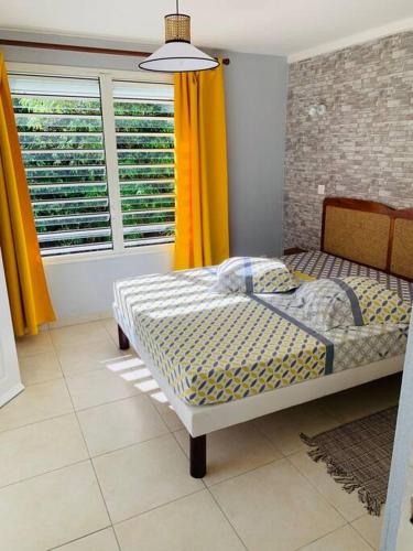 a bedroom with a bed and a window with yellow curtains at Villa Salako, Terre-de-Bas - Bas de Villa in Terre-de-Bas