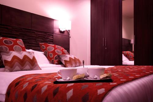 a hotel room with a bed with two cups on it at Bidwood Suite Hotel in Nairobi
