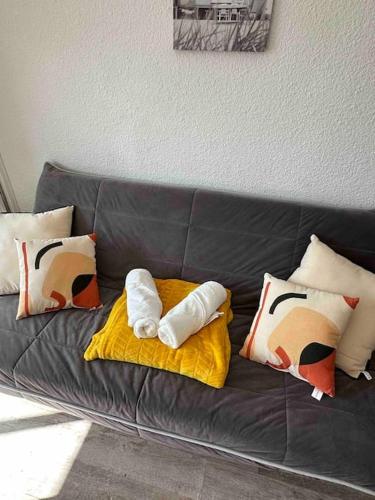 - un canapé noir avec des oreillers dans l'établissement Studio COSY à deux pas de la PLAGE !, à Gruissan