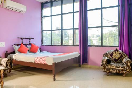 - une chambre avec un lit aux murs violets et des fenêtres dans l'établissement OYO Aradhya Regency, à Konârak