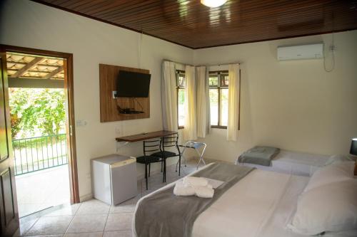 a bedroom with a bed and a desk and a television at Pousada Casa Rosa in Alto Paraíso de Goiás
