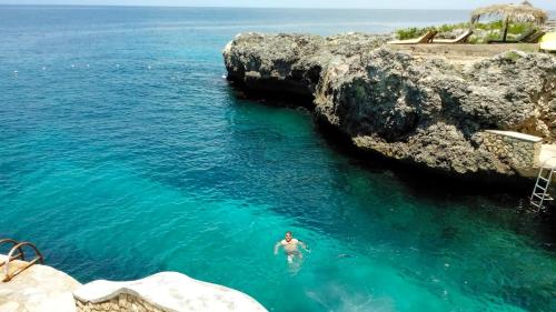 a person swimming in the water near a cliff at Catcha Falling Star in Negril