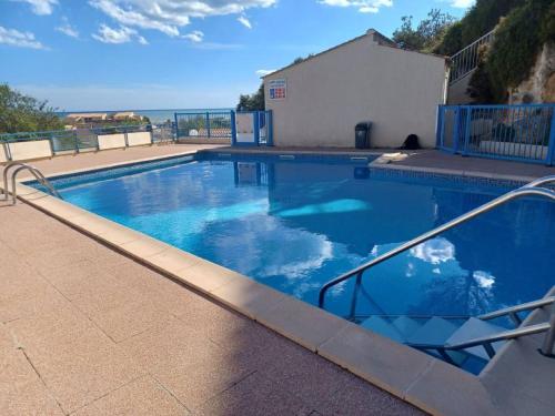 une grande piscine bleue avec vue sur l'océan dans l'établissement DUPLEX PLEINE VUE MER PISCINE parking fibre wifi plage et centre ville a pied st pierre la mer, à Fleury