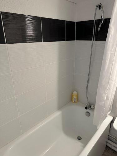 a white bath tub with a black and white tile wall at Studio COSY à deux pas de la PLAGE ! in Gruissan