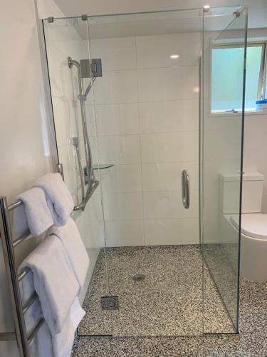 a bathroom with a glass shower stall with towels at Apex Motorlodge in Nelson