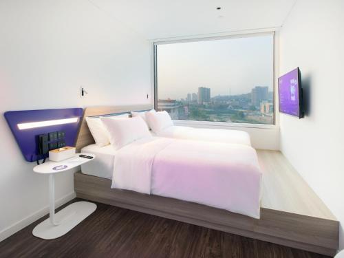 a bedroom with a bed and a tv and a window at SOJO Hotel Lao Cai in Lao Cai