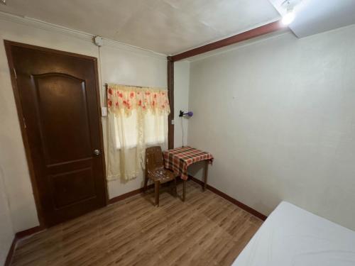 a room with a table and a chair and a door at Darpins Guesthouse in Dauin