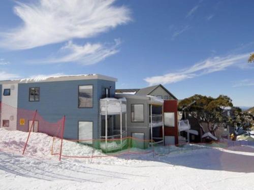 a house in the snow with an orange fence at 2 Higgi Drive - Ski in Ski Out in Mount Hotham