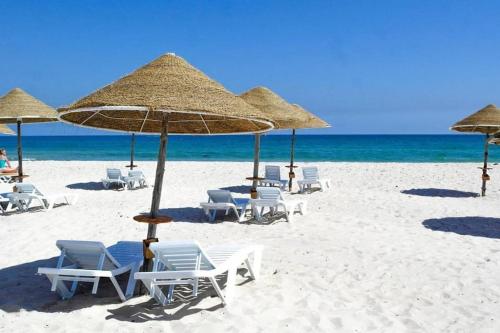 a group of chairs and umbrellas on a beach at Fantastique, luxerieux, agreabel appartement in Monastir