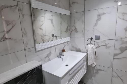 ein weißes Badezimmer mit einem Waschbecken und einem Spiegel in der Unterkunft Fantastique, luxerieux, agreabel appartement in Monastir