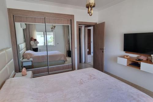 a woman taking a picture of a bedroom with a bed and a mirror at Fantastique, luxerieux, agreabel appartement in Monastir