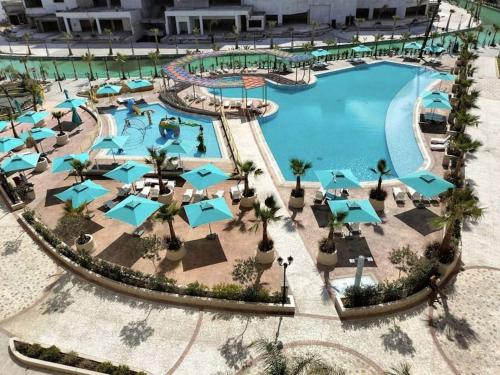 an aerial view of a resort pool with blue umbrellas at Fantastique, luxerieux, agreabel appartement in Monastir