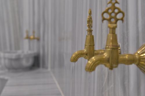 a gold water faucet in a bathroom with a sink at Grand Beyaz Saray Otel in Duzce