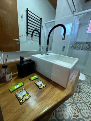 ein Badezimmer mit einem weißen Waschbecken auf einer Holztheke in der Unterkunft Suítes Paz na Montanha - Tesouro Escondido in Campos do Jordão