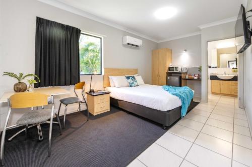 a bedroom with a bed and a desk and a kitchen at Alara Motor Inn in Mackay