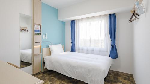 a bedroom with a bed and a window at Toyoko Inn Imba Nihon-idai Ekimae in Inzai