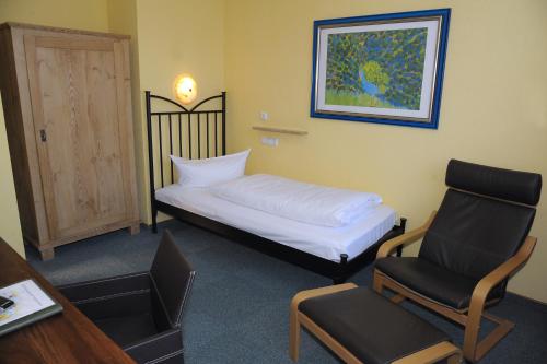 a small bedroom with a bed and a chair at Landhotel Klingerhof in Hösbach