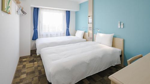 two beds in a room with blue walls and a window at Toyoko Inn Imba Nihon-idai Ekimae in Inzai