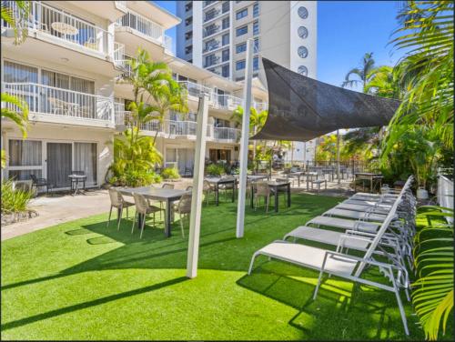 a patio with tables and chairs in front of a building at Outrigger Burleigh in Gold Coast