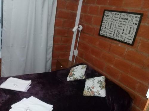 una mesa con 2 almohadas y un cartel en una pared de ladrillo en Las Achiras en San José