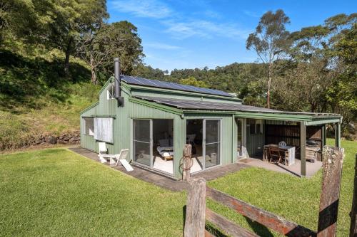 a woman standing in front of a green house at Molla Eco Lodge in Wattamolla