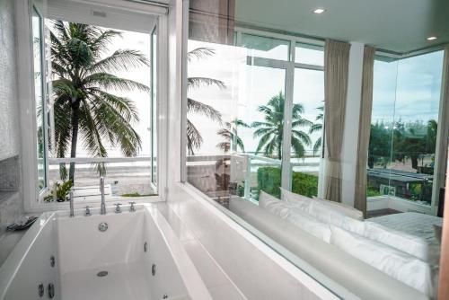 a bath tub in a room with a large window at Tolani Le Bayburi Villas, Hua Hin - Pranburi in Pran Buri