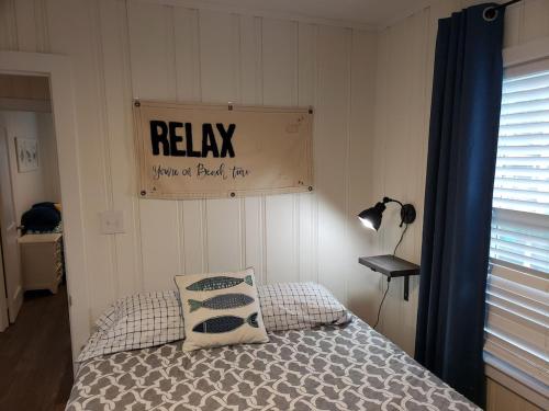 a bedroom with a bed with a sign on the wall at Kure Beach Cottage-Fully Updated--1 block- welcome dogs for modest fee in Kure Beach