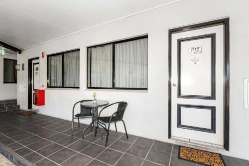 a room with a table and chairs and windows at Alara Motor Inn in Mackay