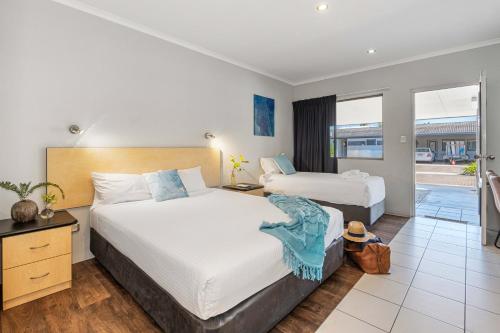 a hotel room with two beds and a balcony at Alara Motor Inn in Mackay