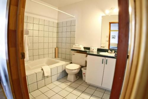 a bathroom with a tub and a toilet and a sink at Hotel - Motel Georges in Tadoussac