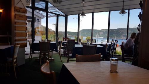 a restaurant with tables and chairs and a view of the water at Hotel - Motel Georges in Tadoussac